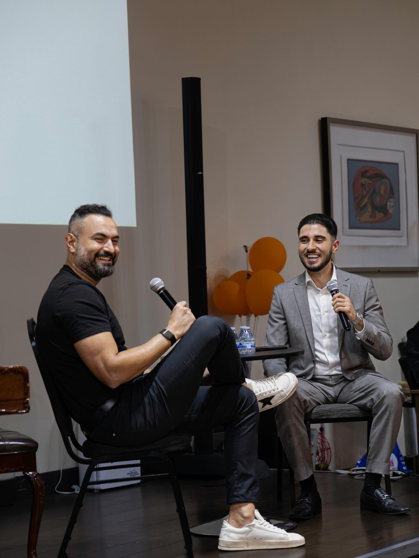 Two speakers laughing on stage at NAYI's Chivichyan Night.